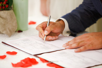 Naklejka premium groom signs marriage certificate with a pen