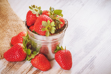 Spring fruits, strawberries in an aluminum bucket on a vintage w