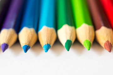 Colored pencils in row on the white paper