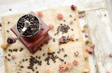 Fototapeta na wymiar Coffee beans and dried roses scattered upon the old map