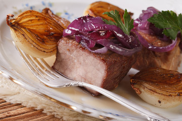 Meat with caramelized onions on a plate closeup. horizontal