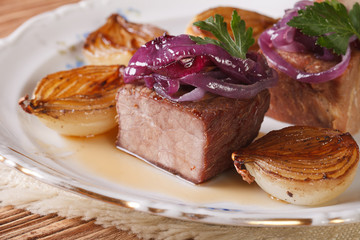 Meat and caramelized onions on a plate close-up. horizontal