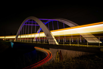 Railway bridge with train and car lights  at night