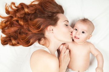 Happy family concept. Beautifull young red haired mother kissing