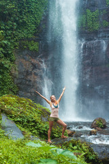 Fototapeta na wymiar Young woman practicing yoga by the waterfall