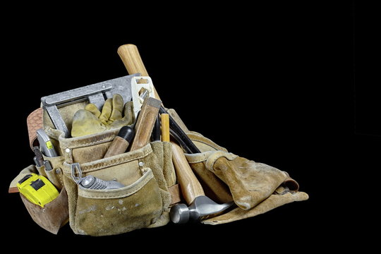Rugged well used carpenters work bags with tools isolated on bla