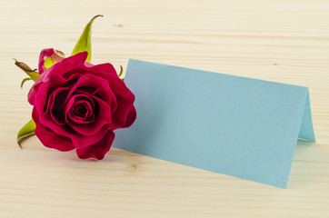 Rose flower with blank invitation card on wooden background