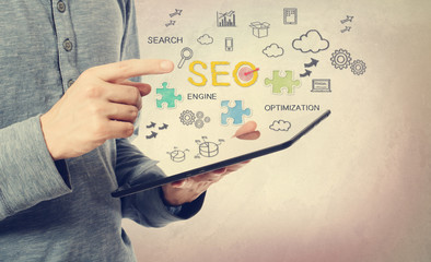 Young man pointing at SEO concept over a tablet