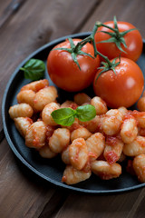 Close-up of italian gnocchi served with tomato sauce and basil