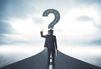 Business person lokking at road with question mark sign