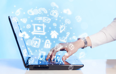 Hand writing on notebook computer with media icons and symbols