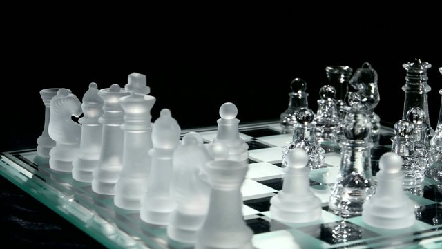 4K. Glass chess on chesboard. Black background.