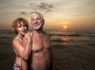 an elderly couple on the sea sunset in swimsuits