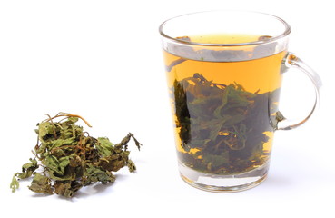 Dried nettle and cup of beverage on white background