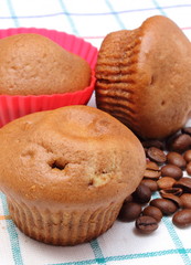 Fresh baked muffins and coffee grains on colorful cloth
