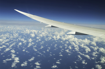 Obraz premium Wing of an airplane flying above the clouds