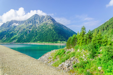 Naklejka na ściany i meble Dam and azure mountain lake and high peaks of the Alps