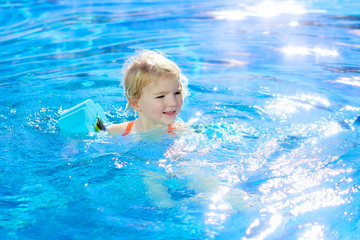 Fototapeta na wymiar Happy toddler girl swimming in the pool