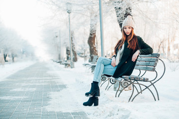 young woman in winter park sitting on the bench