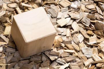 Wooden cube lying on mulch