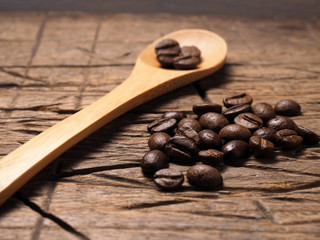 Coffee crop beans on bamboo spoon and wooden texture background