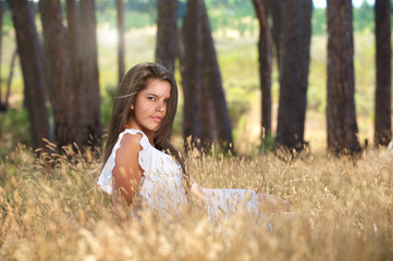 Sensual young woman sitting in a field in nature