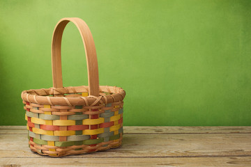 Fototapeta na wymiar Empty basket on wooden table over grunge green background