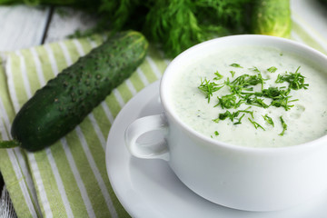 Cucumber soup in bowl on color wooden table background