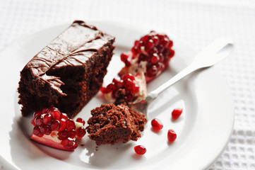 Chocolate cake and pomegranate on a white plate