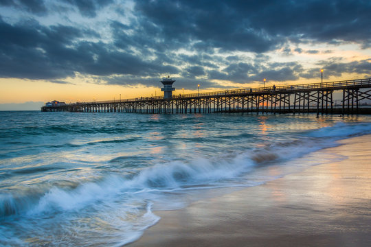 Fototapeta Waves in the Pacific Ocean and the pier at sunset, in Seal Beach