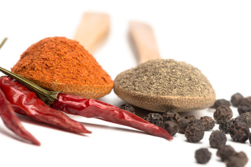 ground red and black pepper in a spoon isolated