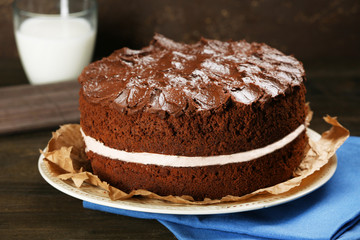 Delicious chocolate cake on table on brown background