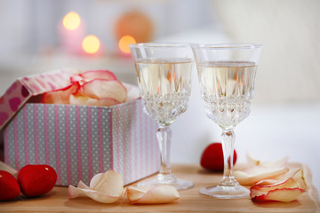 Champagne glasses, gift box and rose petals for celebrating