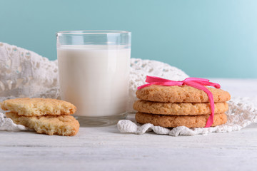 Tasty cookies and glass of milk on color wooden background