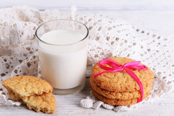 Tasty cookies and glass of milk on color wooden background