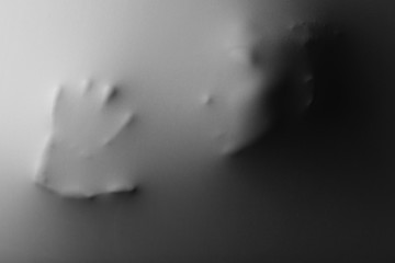 Screaming human face with hand pressing through fabric as