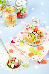 Multicolor candies in glass jars on colorful background