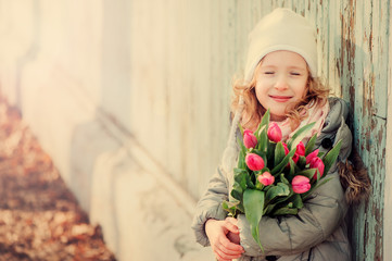 spring portrait of happy child girl with tulips in pastel tones