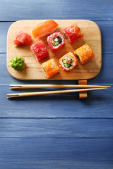 Sushi rolls on tray on color wooden background