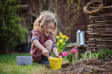 child girl planting flowers in spring garden