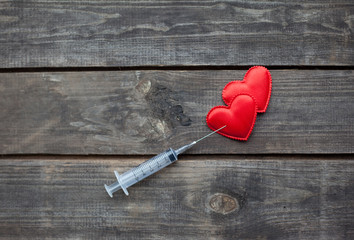 red hearts and syringe on wooden background. Drug Addiction Conc