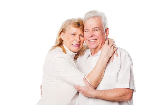 Happy mature couple embracing smiling at camera on white