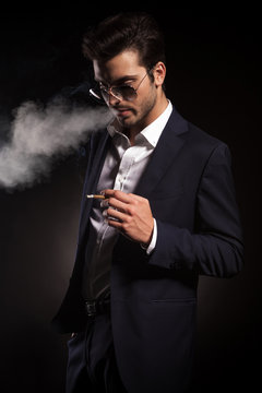 Handsome young business man blowing smoke.