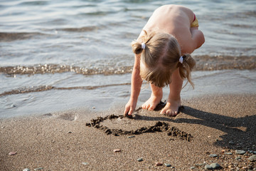 Adorable little girl drawing on sand