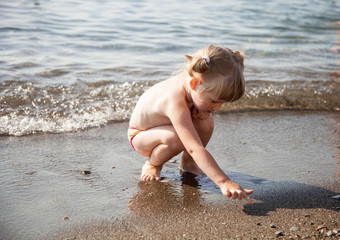 Adorable little girl playing on the seashore