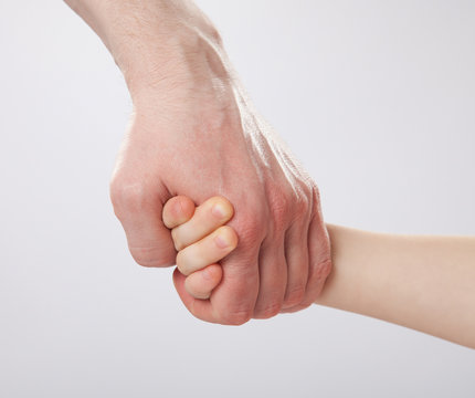 Father holding child's hand, closeup shot on grey background