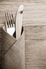 knife and fork at napkin on wood