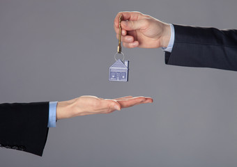 Businessman's hand passing a key to woman's hand