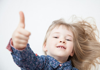 Smiling little girl showing thumb up