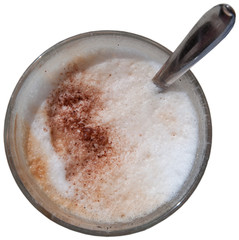 Foamy cappuchino in coffee glass with spoon on white